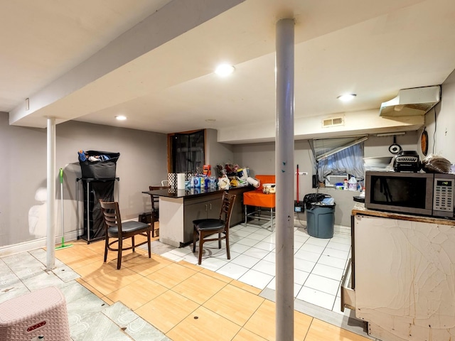 2322 S Trumbull Ave, Chicago, IL 60623 - kitchen with stainless steel microwave, a kitchen bar, light tile patterned floors, recessed lighting, and dark countertops