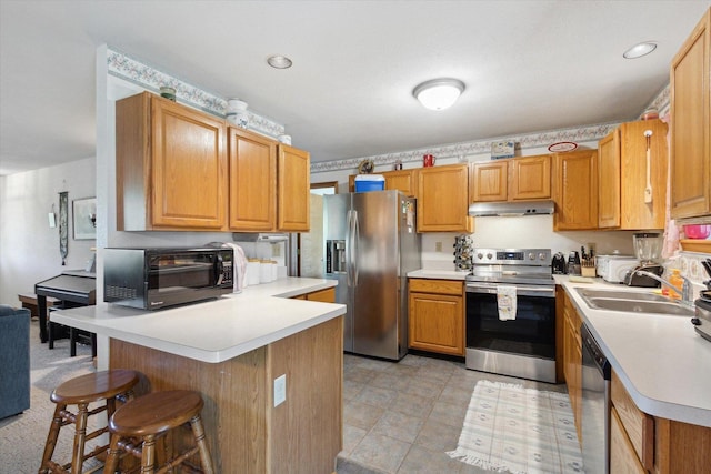5057 Kasch Rd, Pecatonica, IL 61063 - kitchen with stainless steel appliances, under cabinet range hood, a kitchen breakfast bar, a peninsula, and light countertops