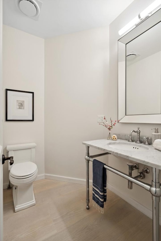 545 W Dickens Ave, Chicago, IL 60614 - half bathroom with toilet, baseboards, wood finished floors, and a sink