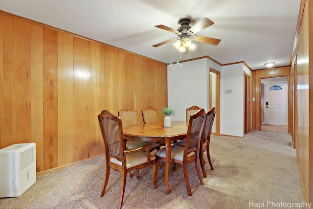 24991 W Forest Dr, Lake Villa, IL 60046 - dining space featuring light carpet, wooden walls, a ceiling fan, baseboards, and crown molding