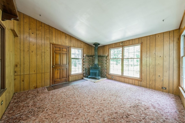 4N051 Wood Dale Rd, Addison, IL 60101 - unfurnished living room featuring a wood stove, healthy amount of natural light, carpet, wood walls, and vaulted ceiling