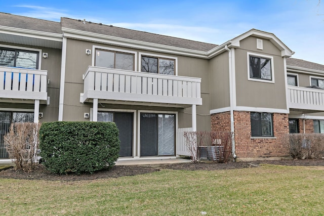 218 Deerpath Ct Unit B2, Schaumburg, IL 60193 - back of property with a balcony, a yard, brick siding, and a shingled roof