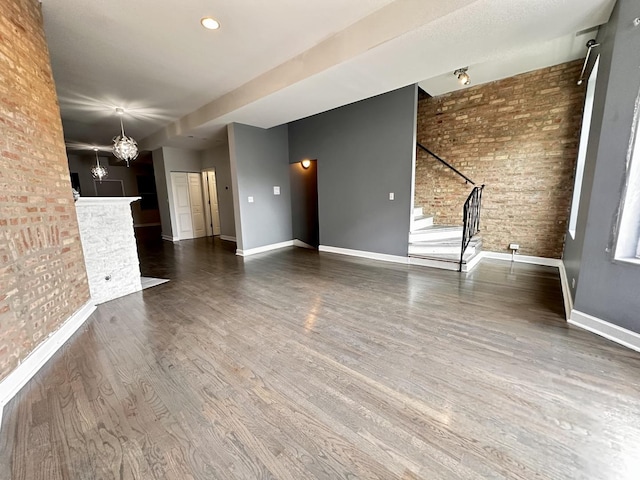 6557 S University Ave Unit 204, Chicago, IL 60637 - unfurnished living room with stairs, baseboards, wood finished floors, a chandelier, and brick wall