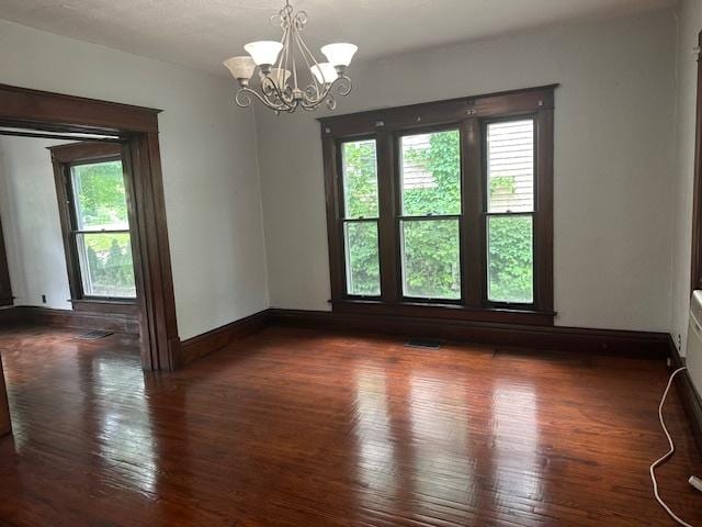 509 N Quincy St, Clinton, IL 61727 - empty room featuring healthy amount of natural light, a chandelier, wood finished floors, and baseboards