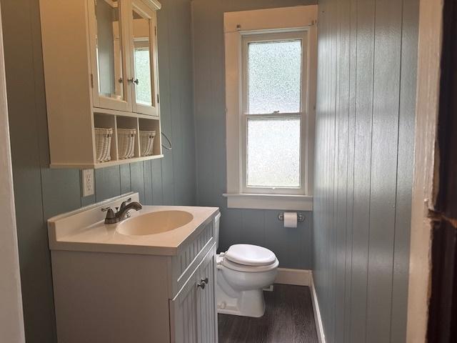509 N Quincy St, Clinton, IL 61727 - bathroom featuring vanity, toilet, baseboards, wood finished floors, and wood walls