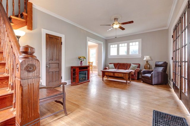 71 S Chestnut St, Aurora, IL 60506 - living room featuring ceiling fan, light wood-style flooring, crown molding, a glass covered fireplace, and stairs