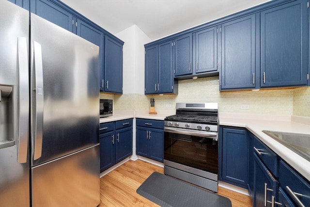 410 Cobblestone Ct, Oswego, IL 60543 - kitchen featuring stainless steel appliances, blue cabinetry, light countertops, and tasteful backsplash