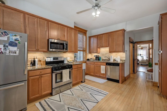 2533 N Kimball Ave, Chicago, IL 60647 - kitchen with stainless steel appliances, a ceiling fan, decorative backsplash, light wood finished floors, and stone countertops