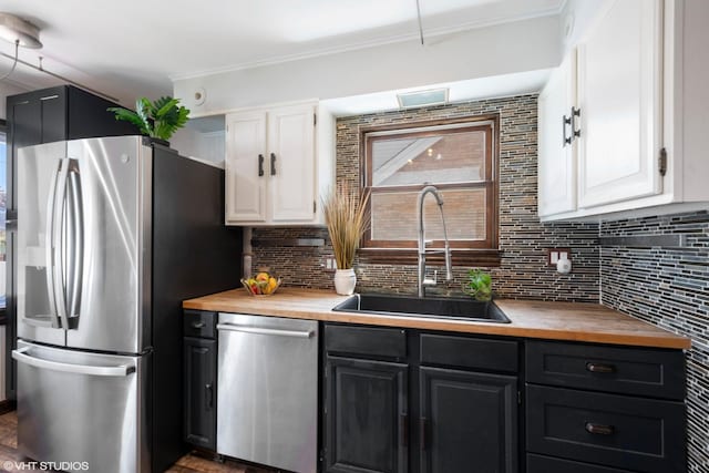 1225 Morgan Ave, La Grange Park, IL 60526 - kitchen featuring appliances with stainless steel finishes, a sink, wooden counters, white cabinets, and decorative backsplash