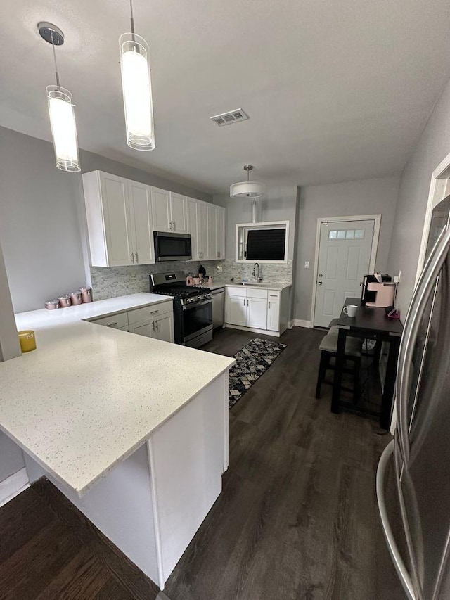 2009 W Garfield Blvd, Chicago, IL 60636 - kitchen featuring stainless steel appliances, a sink, a peninsula, white cabinets, and backsplash