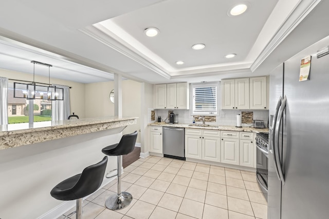 15715 Deerfield Ct Unit 1S, Orland Park, IL 60462 - kitchen featuring appliances with stainless steel finishes, a raised ceiling, a kitchen breakfast bar, backsplash, and recessed lighting