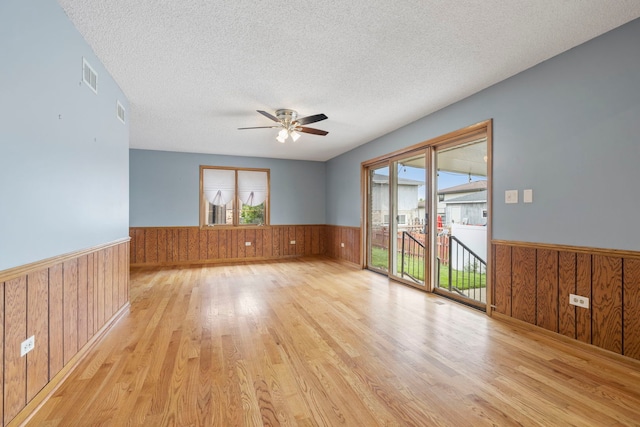 8862 167th St, Orland Hills, IL 60487 - unfurnished room with a wainscoted wall, wood walls, light wood-style floors, a ceiling fan, and a textured ceiling