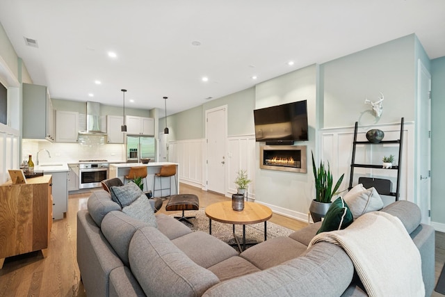 1110 N Marshfield Ave Unit 2, Chicago, IL 60622 - living room with light wood-type flooring, a lit fireplace, a wainscoted wall, a decorative wall, and recessed lighting