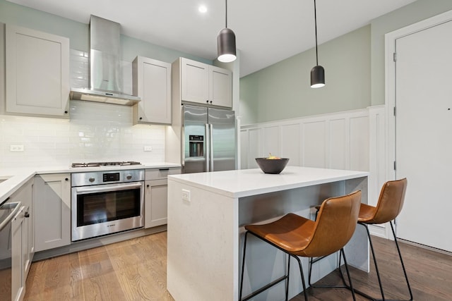 1110 N Marshfield Ave Unit 2, Chicago, IL 60622 - kitchen with appliances with stainless steel finishes, wall chimney exhaust hood, light wood finished floors, decorative backsplash, and a wainscoted wall