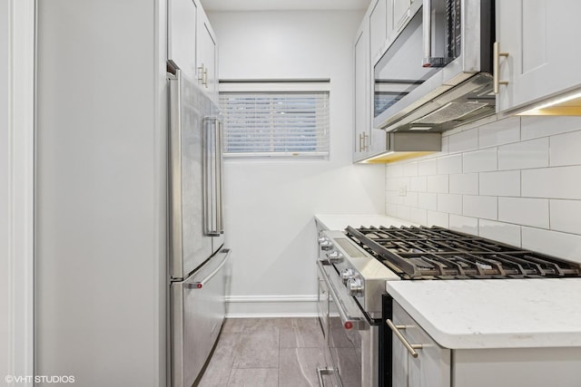 534 W Brompton Ave Unit 1N, Chicago, IL 60657 - kitchen featuring high end appliances, backsplash, baseboards, white cabinets, and light stone counters