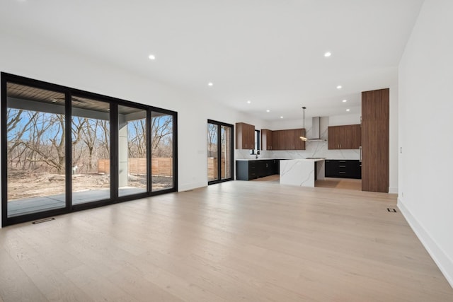8833 Birch Ave, Morton Grove, IL 60053 - unfurnished living room featuring baseboards, light wood-style floors, healthy amount of natural light, recessed lighting, and a sink
