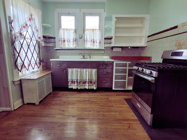 318 W 112th St, Chicago, IL 60628 - kitchen featuring stainless steel range with gas stovetop, open shelves, dark wood-style floors, radiator heating unit, and a sink