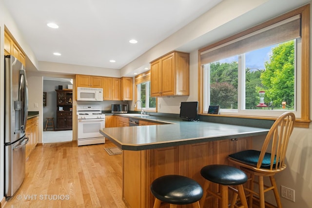 717 Burris Ave, Lake Bluff, IL 60044 - kitchen featuring appliances with stainless steel finishes, a peninsula, light wood-type flooring, a breakfast bar, and recessed lighting