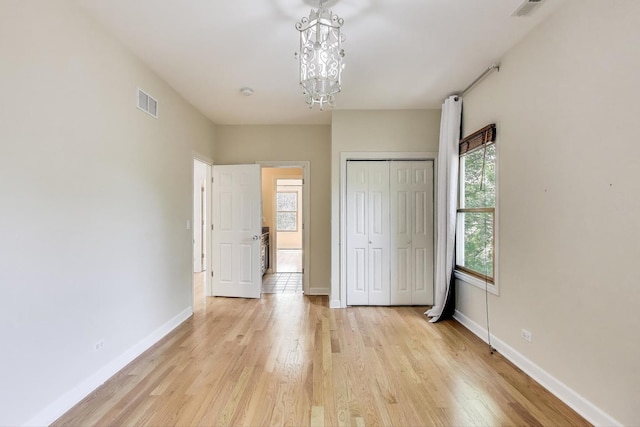 2430 Hastings Ave, Evanston, IL 60201 - unfurnished bedroom with light wood-style flooring, multiple windows, a chandelier, and a closet