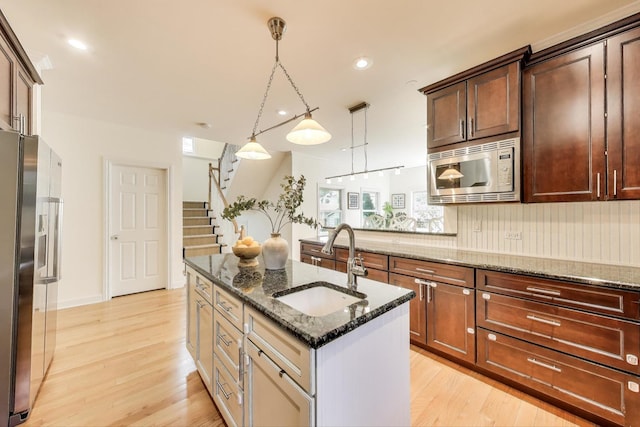 2430 Hastings Ave, Evanston, IL 60201 - kitchen with appliances with stainless steel finishes, light wood-style flooring, an island with sink, dark stone countertops, and recessed lighting