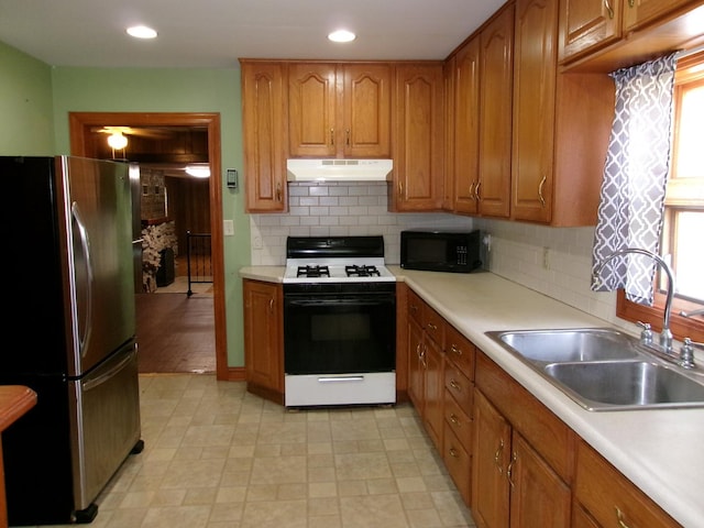 143 W Scott St, Seneca, IL 61360 - kitchen with white gas range oven, freestanding refrigerator, under cabinet range hood, black microwave, and brown cabinetry