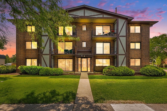 7131 166th St Unit 101, Tinley Park, IL 60477 - view of front facade featuring a balcony, a front lawn, brick siding, and stucco siding