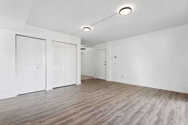 7131 166th St Unit 101, Tinley Park, IL 60477 - unfurnished bedroom with multiple closets, wood finished floors, and baseboards