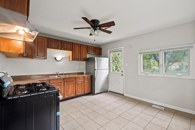 21643 Merrill Ave, Sauk Village, IL 60411 - kitchen featuring gas stove, freestanding refrigerator, a sink, a ceiling fan, and brown cabinetry