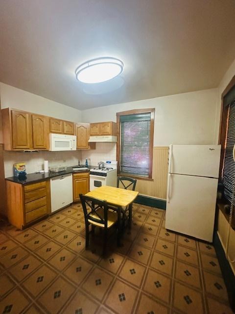 4001 S Albany Ave, Chicago, IL 60632 - kitchen with white appliances, under cabinet range hood, a wainscoted wall, and dark countertops