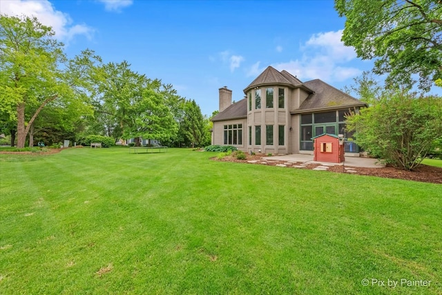 7530 Inverway Dr, Lakewood, IL 60014 - rear view of house with a sunroom, a lawn, and a chimney