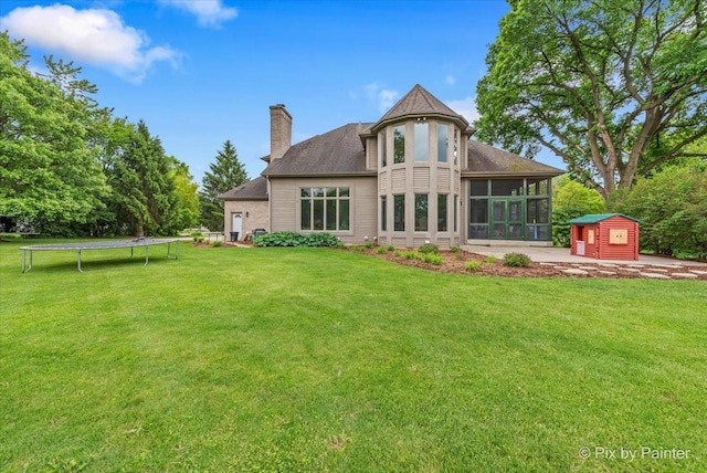 7530 Inverway Dr, Lakewood, IL 60014 - rear view of property with a trampoline, a sunroom, a chimney, and a yard