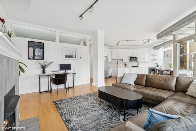 1001 W Madison St Unit 211, Chicago, IL 60607 - living area featuring rail lighting, a fireplace with flush hearth, beverage cooler, light wood finished floors, and baseboards