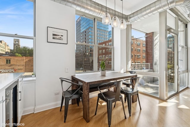 1001 W Madison St Unit 211, Chicago, IL 60607 - dining space featuring wine cooler, wood finished floors, a chandelier, and baseboards