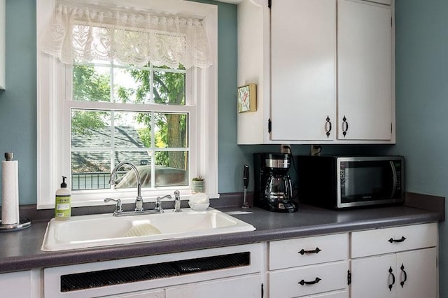 3803 Charles St, Rockford, IL 61108 - kitchen featuring stainless steel microwave, a sink, white cabinets, dark countertops, and dishwashing machine