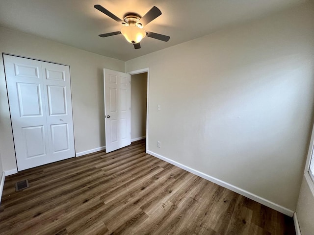 2422 E Washington St, Urbana, IL 61802 - unfurnished bedroom with dark wood-type flooring, a closet, and a ceiling fan
