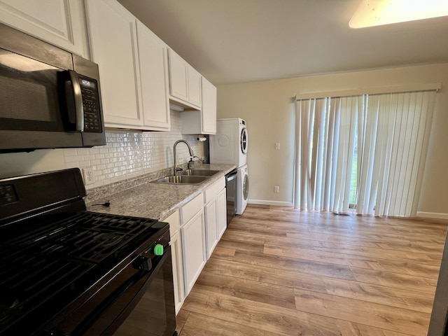 2422 E Washington St, Urbana, IL 61802 - kitchen featuring stainless steel appliances, estacked washer and dryer, light wood-style floors, backsplash, and white cabinetry