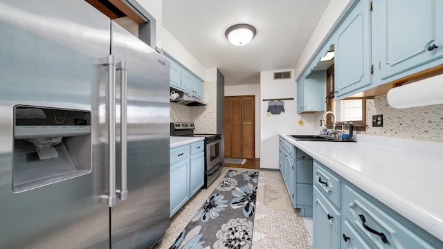 113 Maple Ave, Mount Morris, IL 61054 - kitchen featuring stainless steel appliances, blue cabinets, a sink, under cabinet range hood, and decorative backsplash