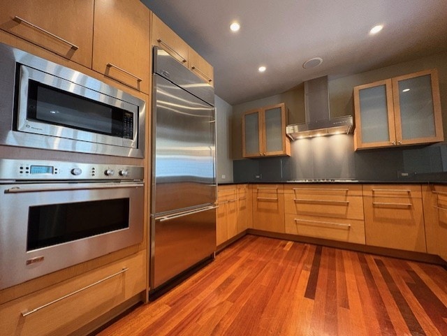 270 E Pearson St Unit 602, Chicago, IL 60611 - kitchen with built in appliances, wall chimney range hood, light wood-type flooring, recessed lighting, and glass insert cabinets