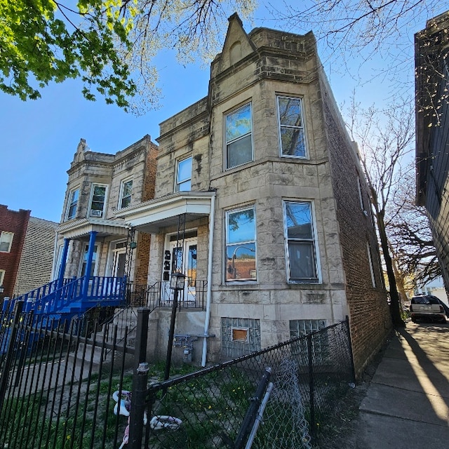 212 N Leamington Ave, Chicago, IL 60644 - view of front of house featuring a fenced front yard, a porch, and stone siding