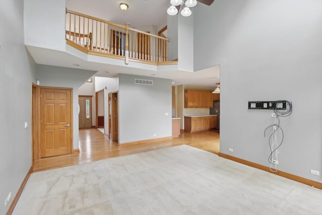 548 Asbury Dr, Aurora, IL 60502 - unfurnished living room featuring light colored carpet, a ceiling fan, baseboards, a high ceiling, and light wood-style floors
