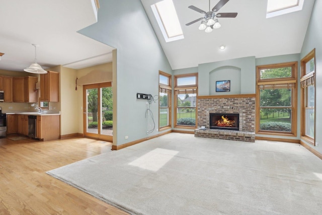 548 Asbury Dr, Aurora, IL 60502 - unfurnished living room featuring a brick fireplace, ceiling fan, baseboards, a skylight, and high vaulted ceiling