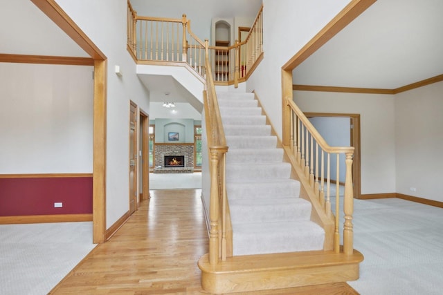 548 Asbury Dr, Aurora, IL 60502 - stairway with carpet, baseboards, a fireplace, a high ceiling, and crown molding