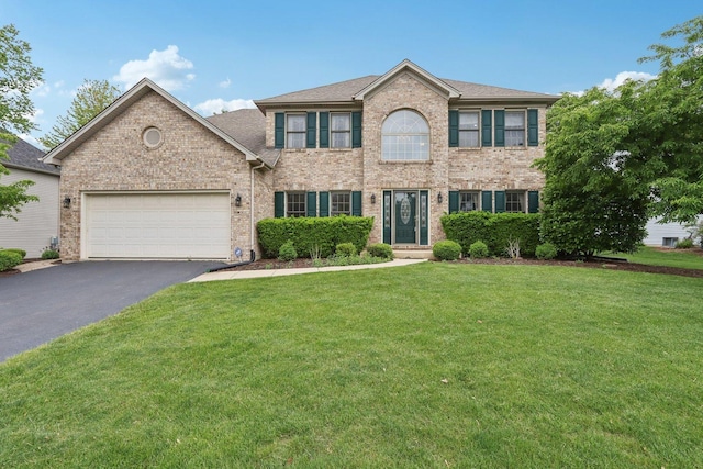 548 Asbury Dr, Aurora, IL 60502 - colonial inspired home with asphalt driveway, brick siding, a front yard, and an attached garage