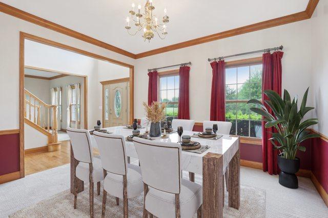 548 Asbury Dr, Aurora, IL 60502 - dining area with a chandelier, stairway, light colored carpet, crown molding, and healthy amount of natural light