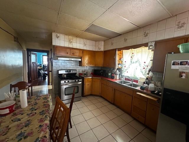 2428 N Lorel Ave, Chicago, IL 60639 - kitchen with stainless steel appliances, under cabinet range hood, light tile patterned floors, tasteful backsplash, and a sink