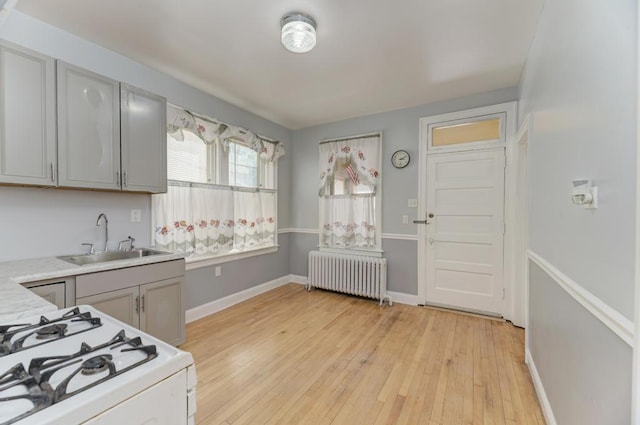 6834 S Rockwell St, Chicago, IL 60629 - kitchen featuring radiator, a sink, gas range gas stove, light countertops, and light wood-style flooring