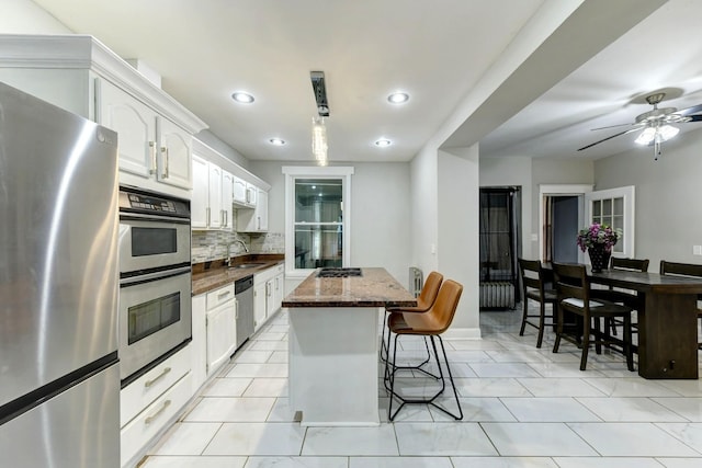 614 E 92nd Pl, Chicago, IL 60619 - kitchen featuring stainless steel appliances, a sink, a kitchen breakfast bar, a kitchen island, and backsplash