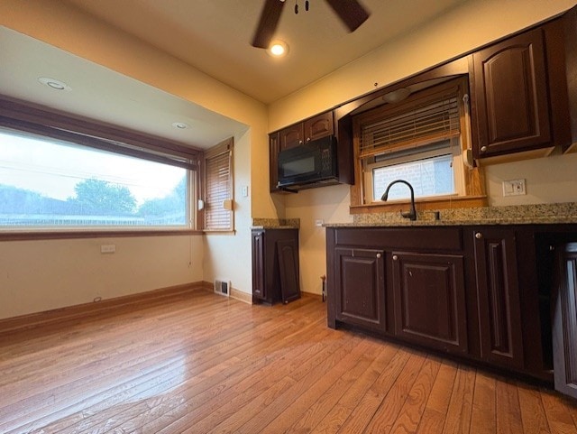 8834 S E End Ave, Chicago, IL 60617 - kitchen with black microwave, dark brown cabinets, light wood-style flooring, ceiling fan, and a sink