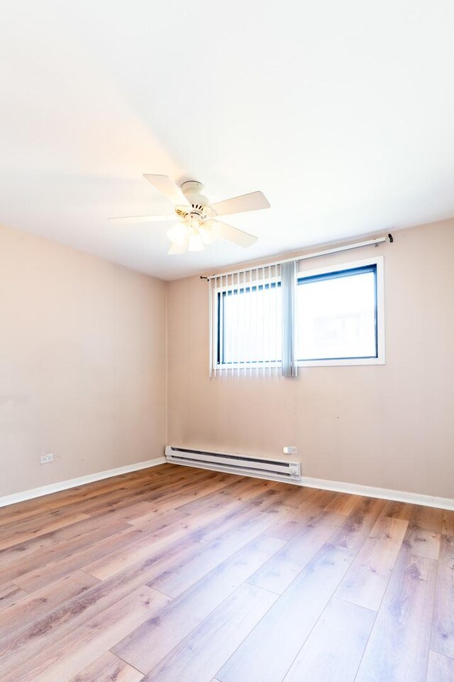 6319 W 64th Pl Unit 1N, Chicago, IL 60638 - unfurnished room with a baseboard heating unit, wood finished floors, and a ceiling fan