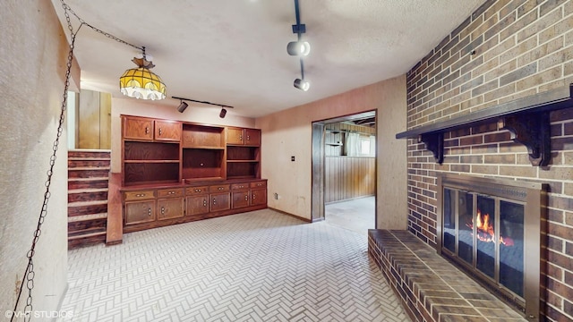 959 S Fern Ave, Elmhurst, IL 60126 - unfurnished living room featuring a brick fireplace, track lighting, stairs, and light colored carpet